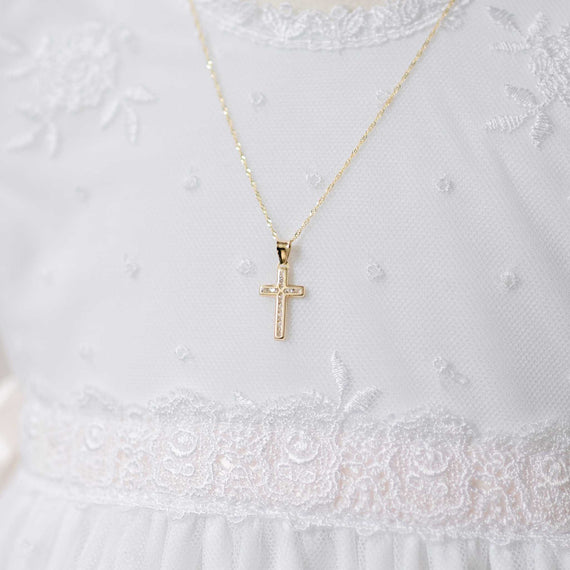 Gold cross with crystals necklace on a white lace garment