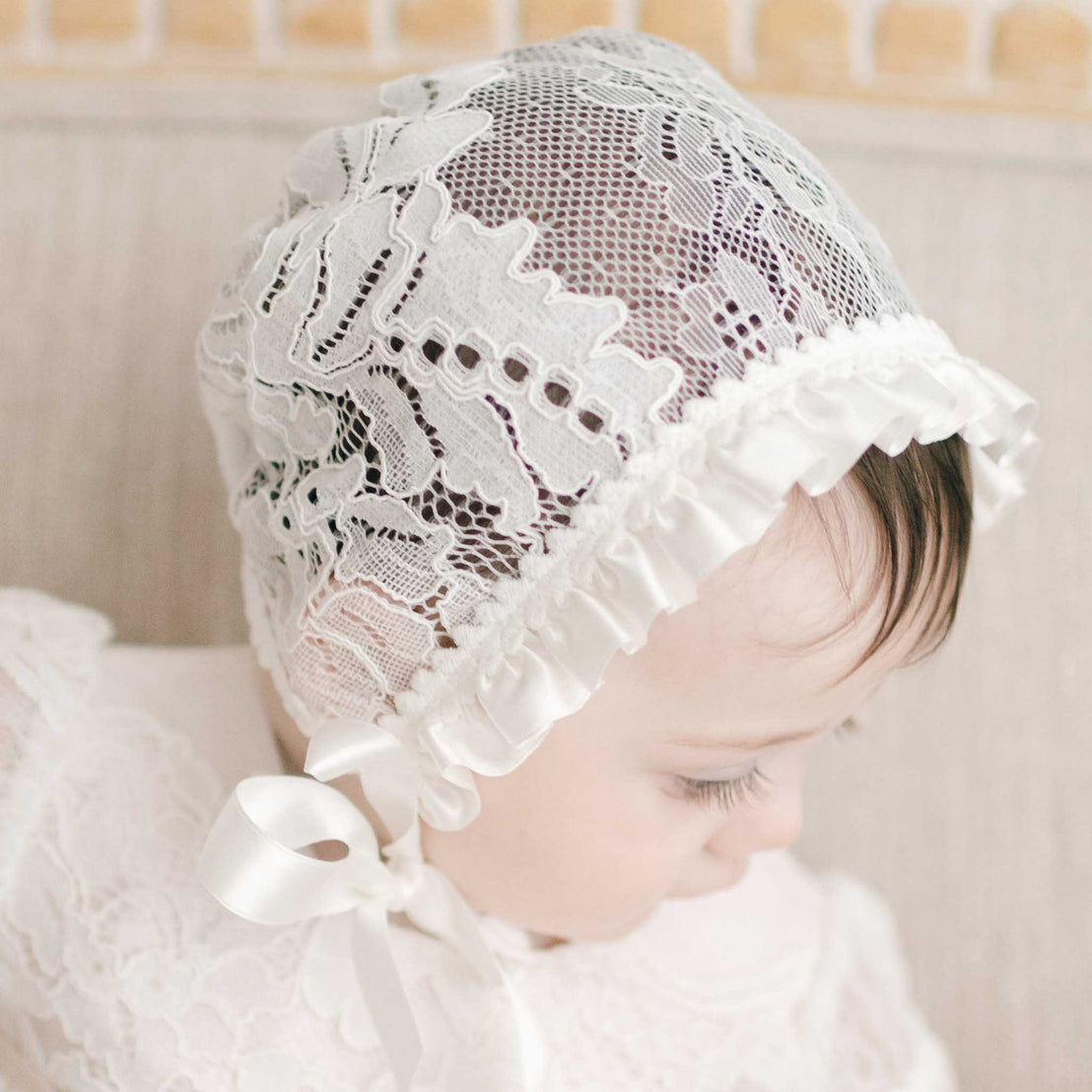 Side profile of baby girl wearing the Victoria Lace Christening Bonnet.