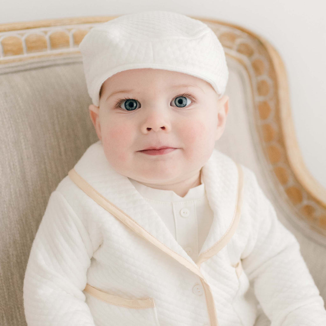 Close up photo of a baby boy wearing the Liam 3-Piece Suit Jacket and Newsboy Cap