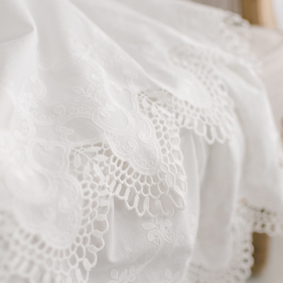Close-up detail of the Lily Christening Gown skirt showcasing the two-tiered lace skirt with cotton eyelet lace and scalloped edges
