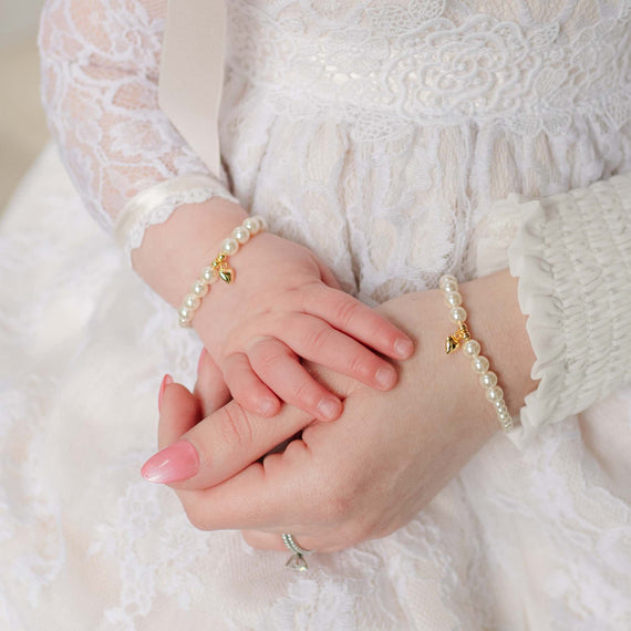 Close-up of mother and baby wearing pearl bracelets with a soft focus background
