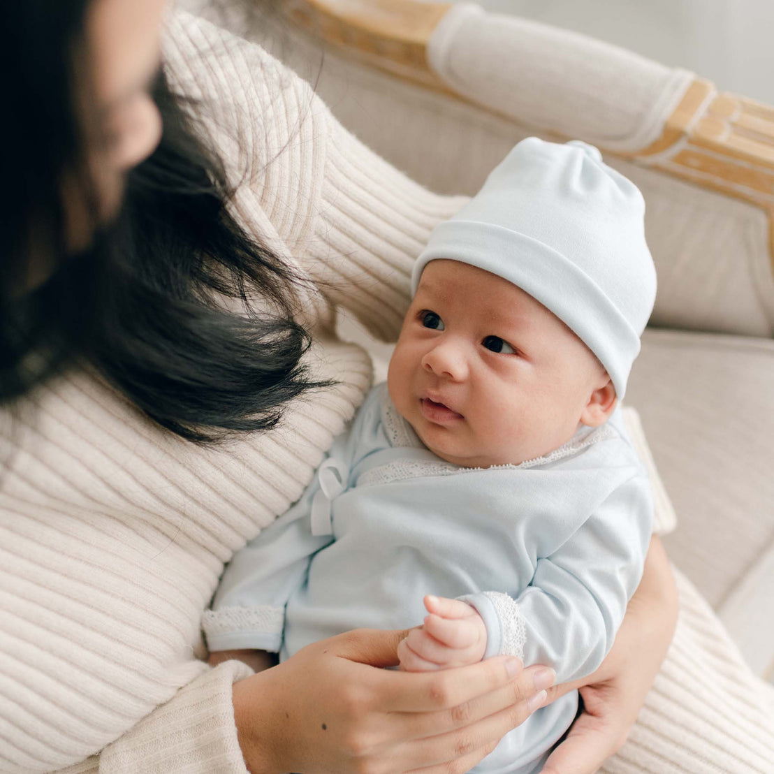 Baby boy looking at Mom showing front of blue cotton knot hat