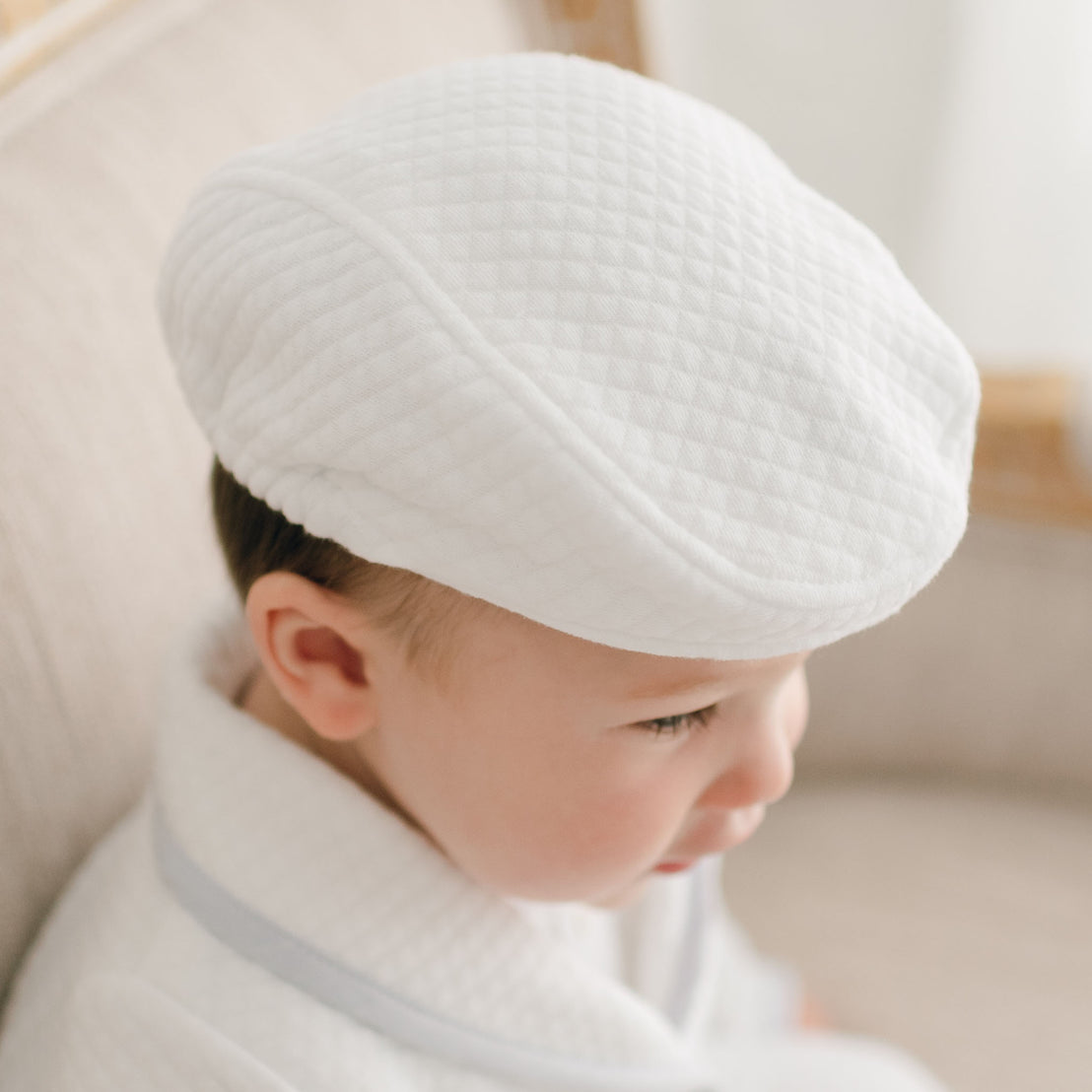 Close-up picture of a baby boy wearing the Harrison Quilted Newsboy Cap crafted with quilted cotton