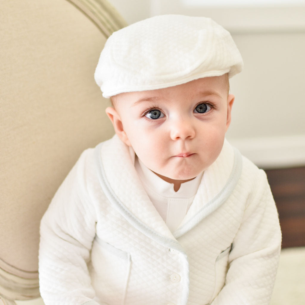 Baby boy sitting on a chair wearing the Harrison 3-Piece Pants Suit made with plush white quilted cotton jack, pants, and hat
