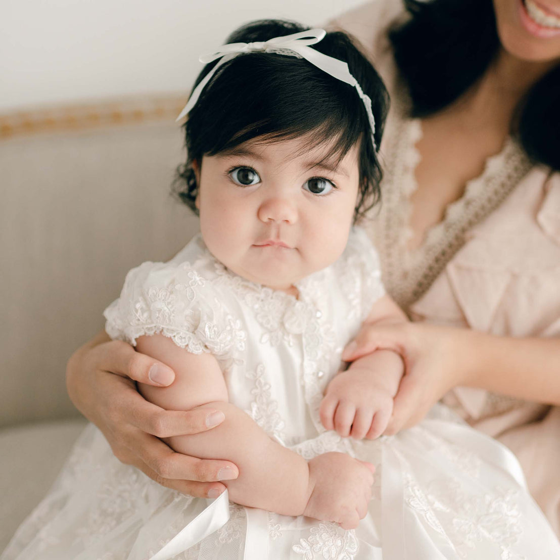 Baby girl and mom sitting with traditional heirloom style silk and lace christening gown and headband