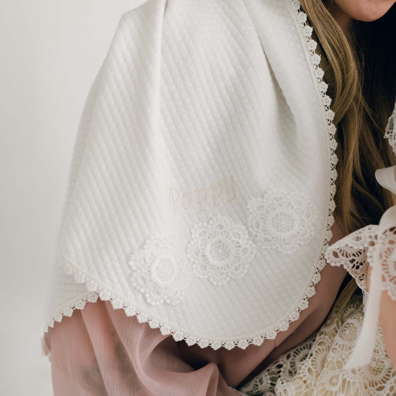 Close-up of the Poppy Personalized Blanket in soft quilted fabric, embroidered with the name 'Poppy' and adorned with delicate floral lace trim.