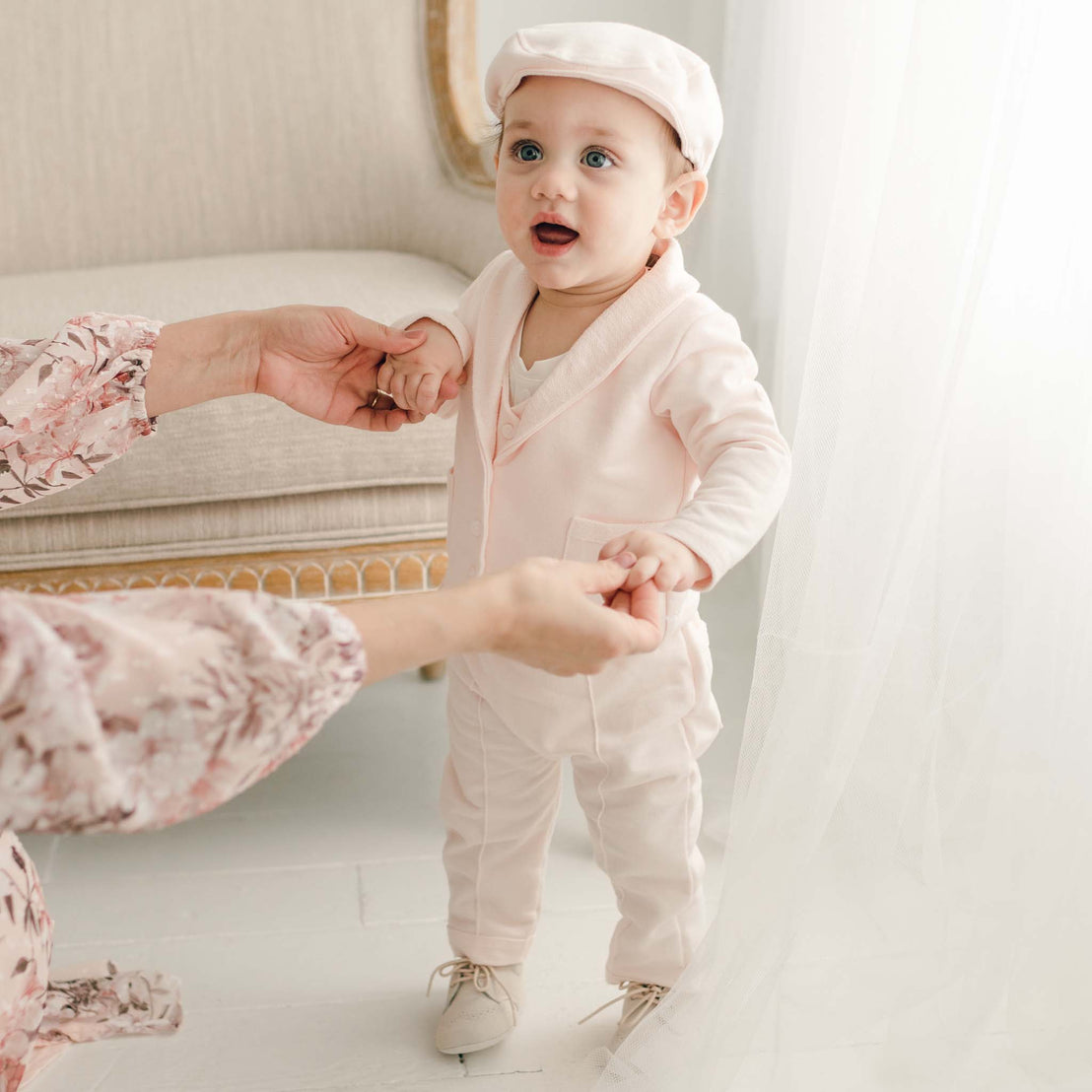 Baby boy standing in blush suit and newsboy cap
