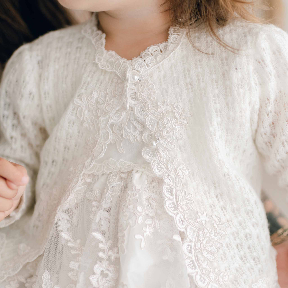 Close up photo of the knit detail on the Penelope knit christening sweater, edged with a floral lace.
