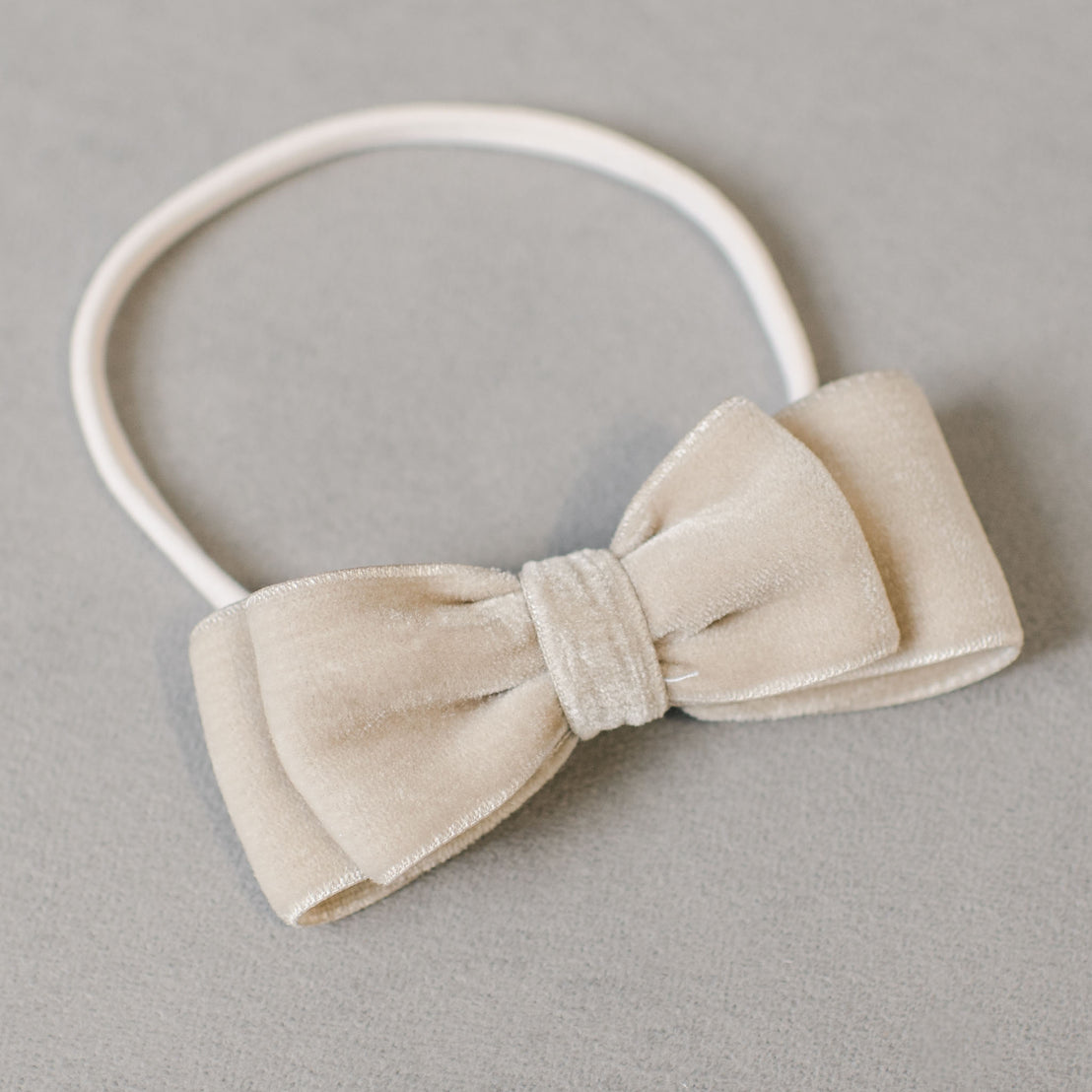 An elegant Grace Velvet Bow Headband on a hand-stretched nylon band, displayed on a gray background.