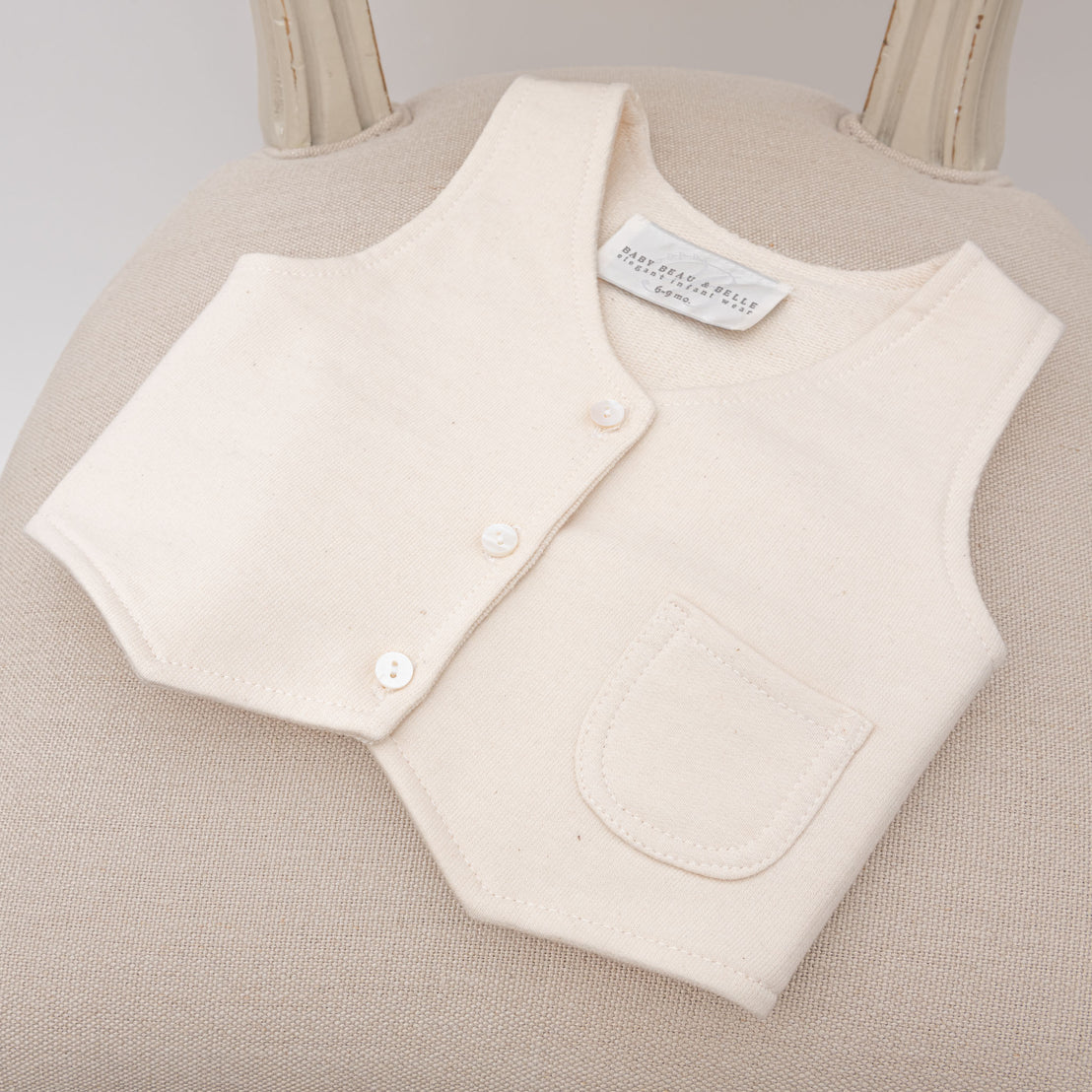 The Milo Tan Vest placed on an upholstered chair, showing its structured design and subtle color.