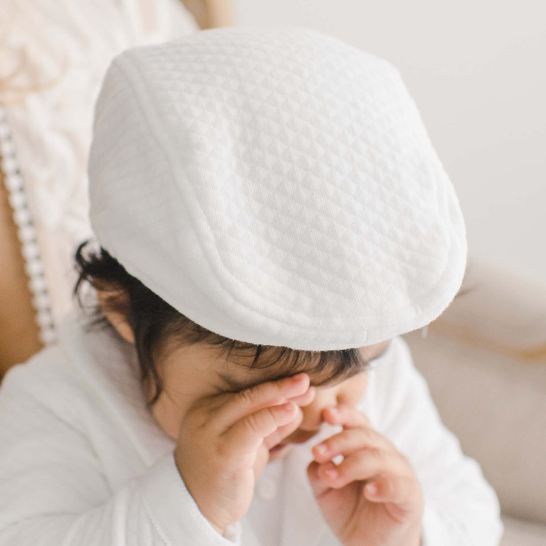 Baby boy wearing the Elijah Newsboy Cap. The photo shows the top of the hat and the white textured cotton that it is crafted from