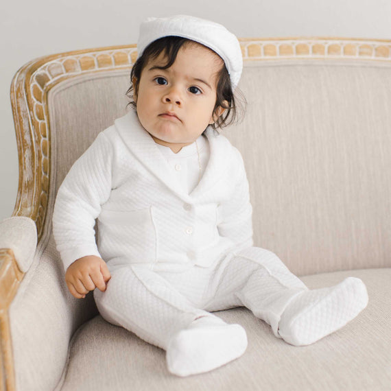 Baby boy sitting on a chair wearing the Elijah 3-Piece Suit made from 100% white textured cotton jacket and pants, and a white cotton / rayon blend shirt 