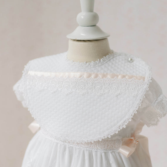 Close up photo of the Melissa Bib on a mannequin against a plain background. Details show white quilted textured cotton with Venice lace and silk ribbon. Perfect baptism gift ideas.