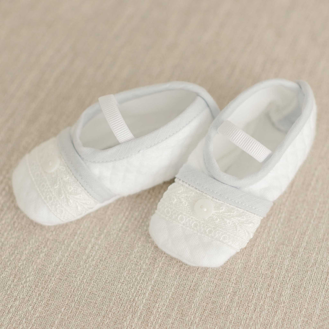 Harrison Booties displayed on a beige fabric background, showcasing lace accents and a button embellishment.