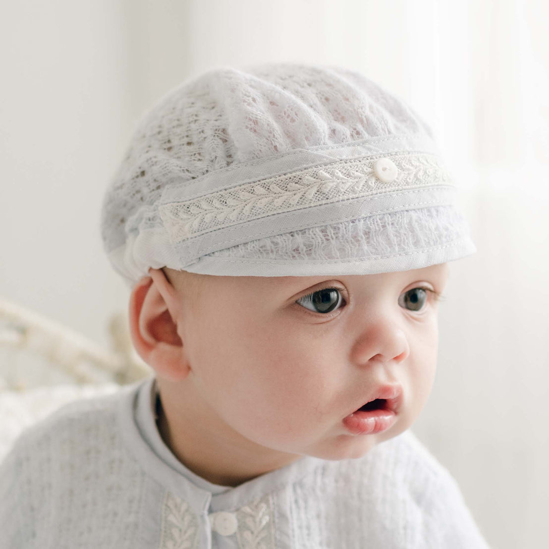 Close-up of a baby wearing the Harrison Blue Knit Hat, showcasing the intricate lace texture and ivory trim detail.