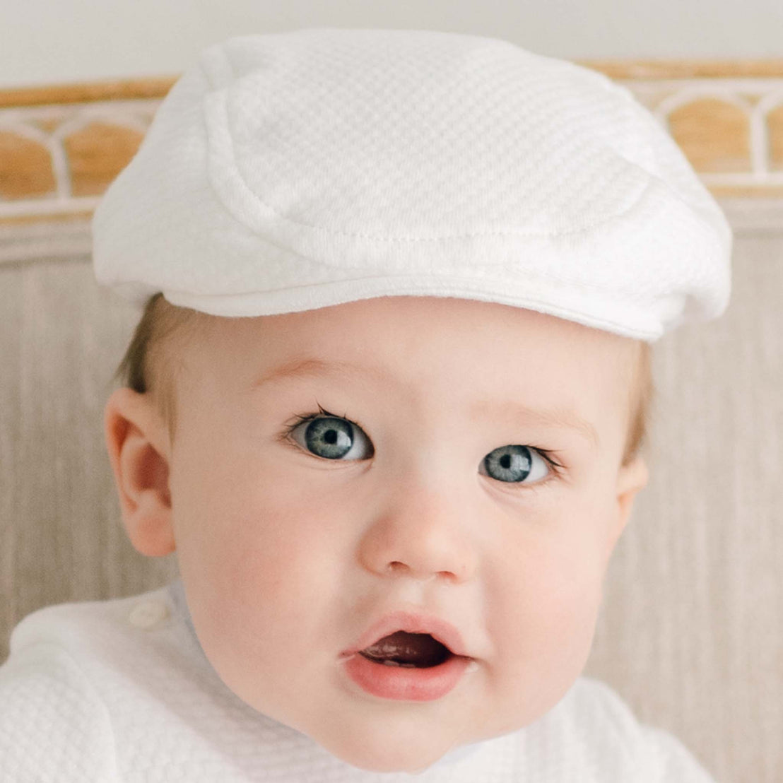 A baby smiling while wearing the Harrison Textured Newsboy Cap, paired with a coordinating outfit.