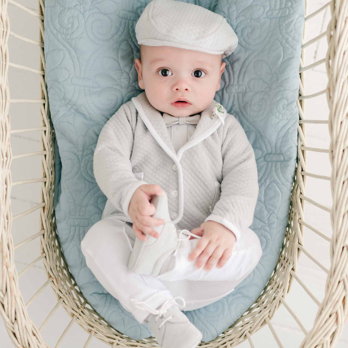 A baby in a crib dressed adorably in his Asher Grey 3-Piece Suit, perfect for any special occasion.