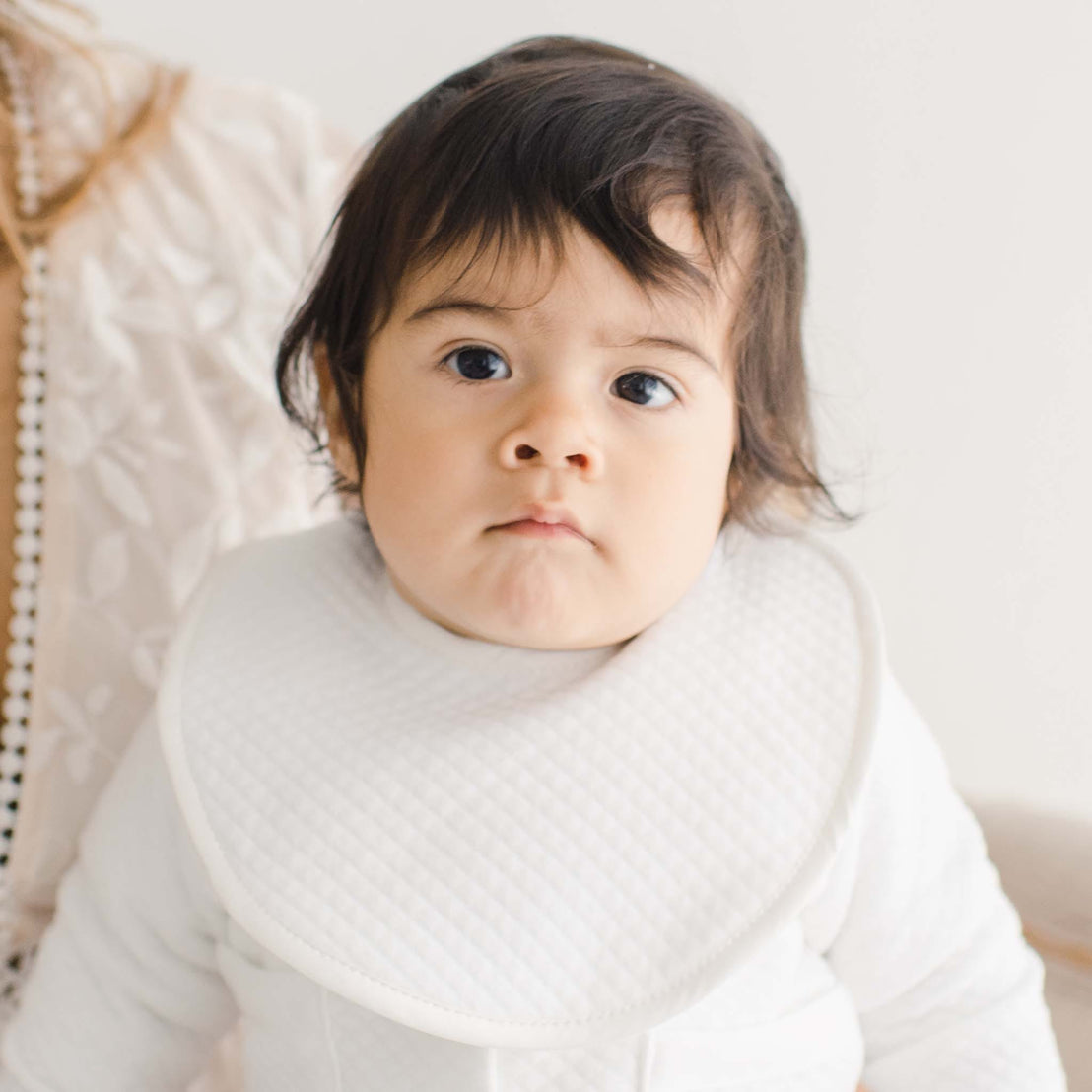 Baby boy wearing the Elijah Bib made with soft 100% white quilted cotton and featuring a soft white silk
