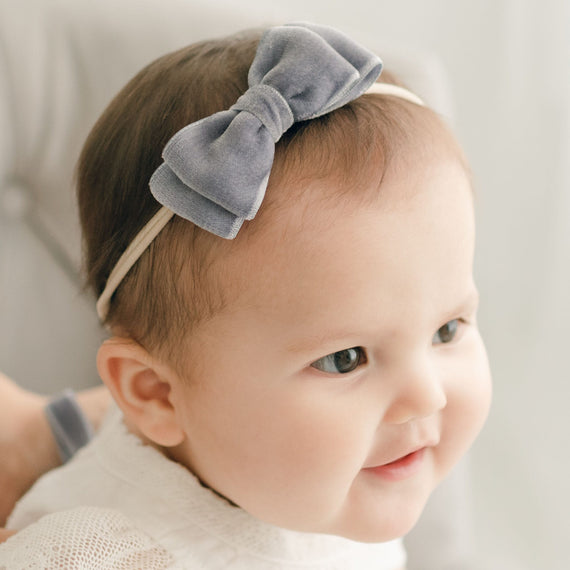 Baby girl wearing the heather Emily Velvet Bow Headband with hand-stretched nylon band.