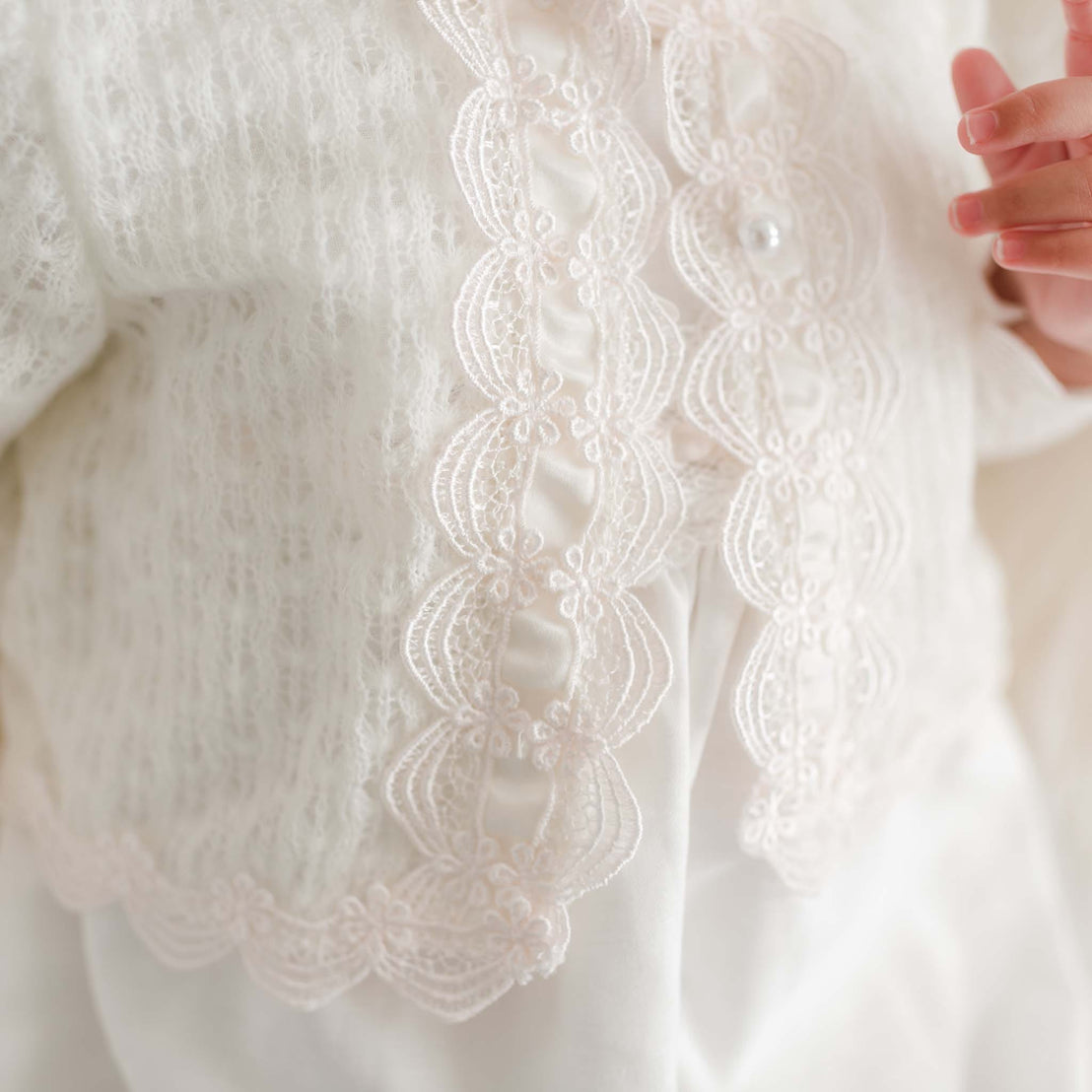 Close-up of a white knit sweater with a soft focus background.