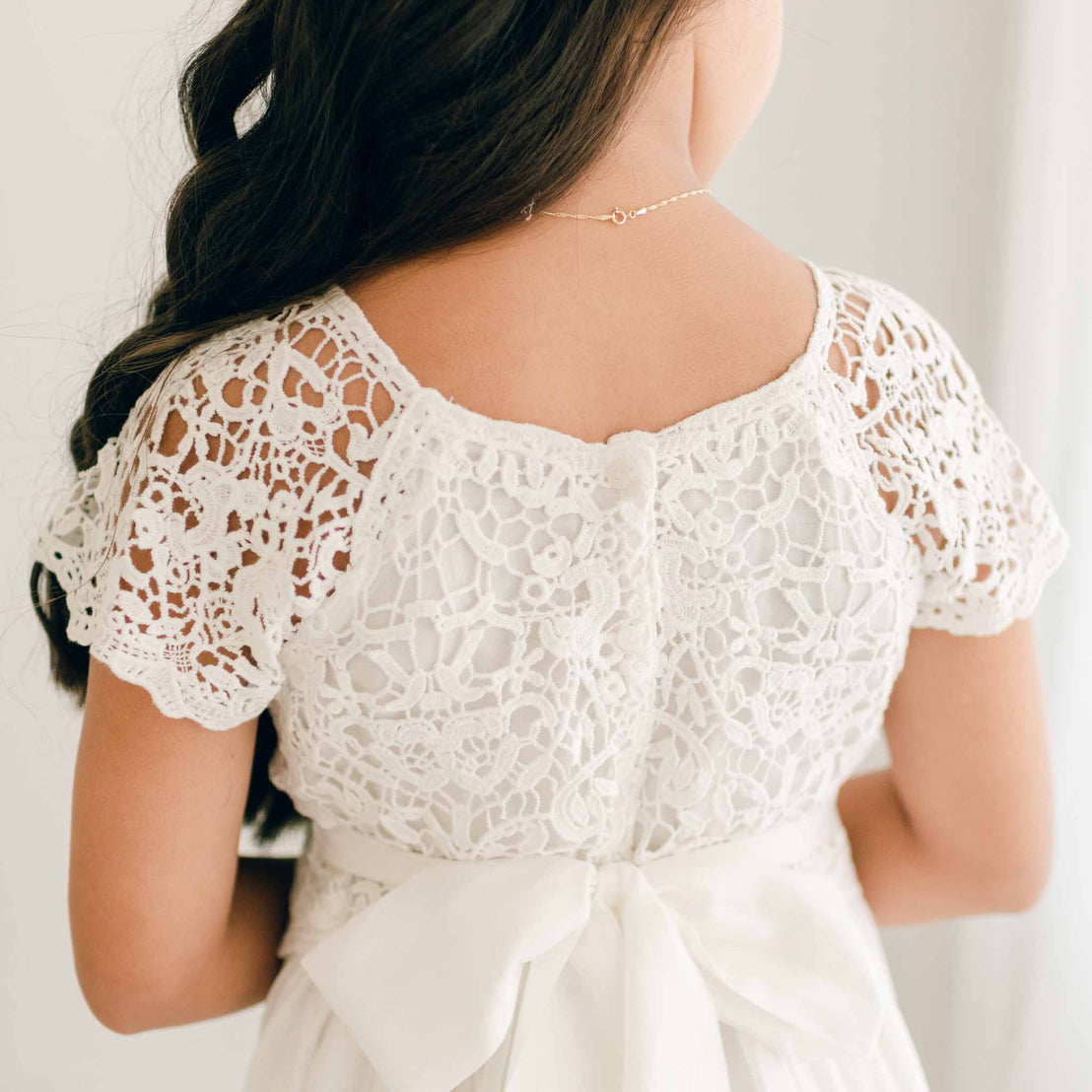 Close-up of the lace back bodice of the Grace Girls Lace Dress, highlighting the button closure and scalloped sleeves.
