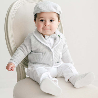 Baby wearing the Grayson 3-Piece Suit with quilted jacket, white pants, matching cap, and bow tie seated on a light chair.