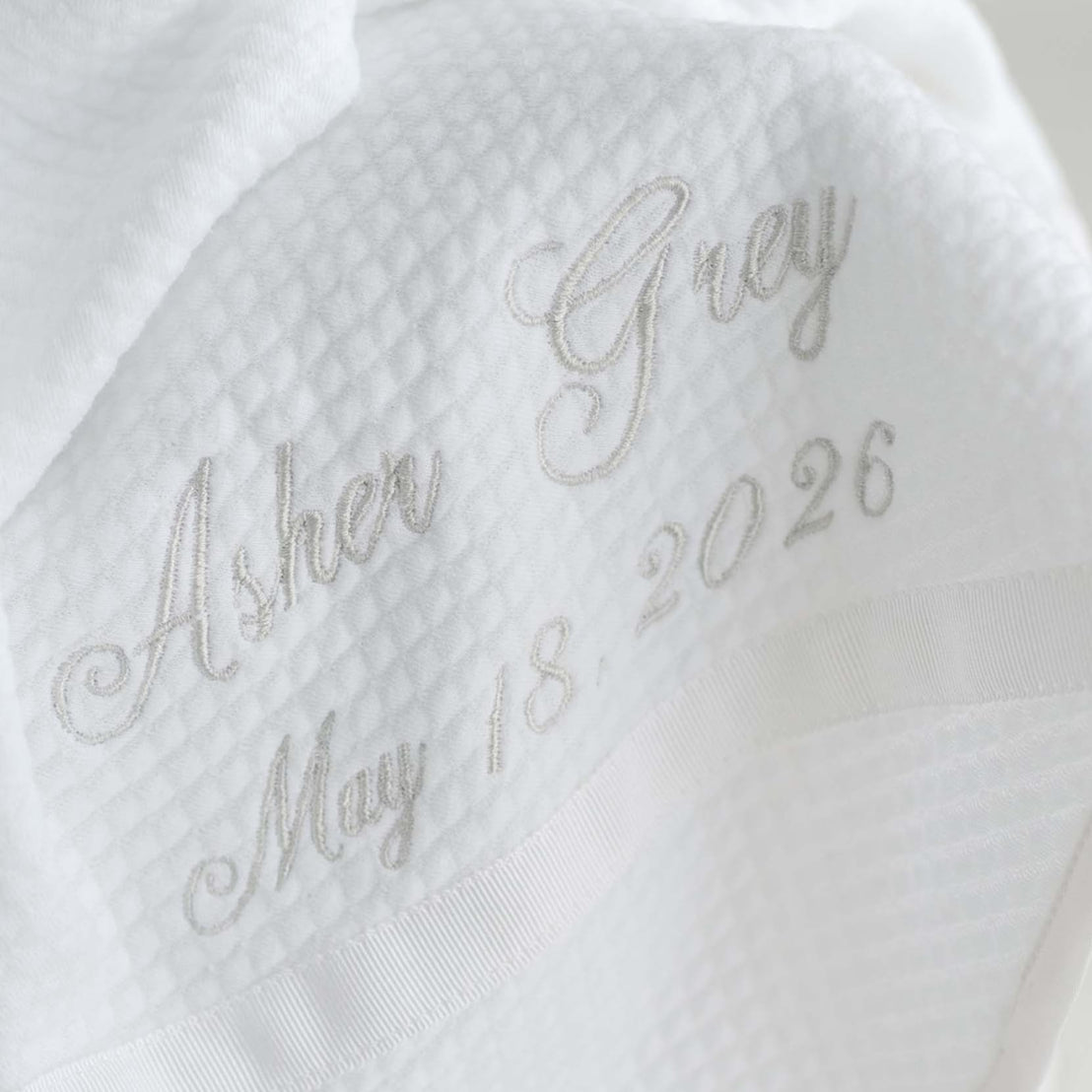 White quilt blanket with embroidered text on a light background.