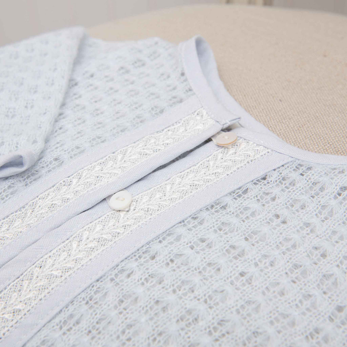 Close-up detail of the blue knit sweater, showcasing the fine lace trim and pearl-like buttons on the front.