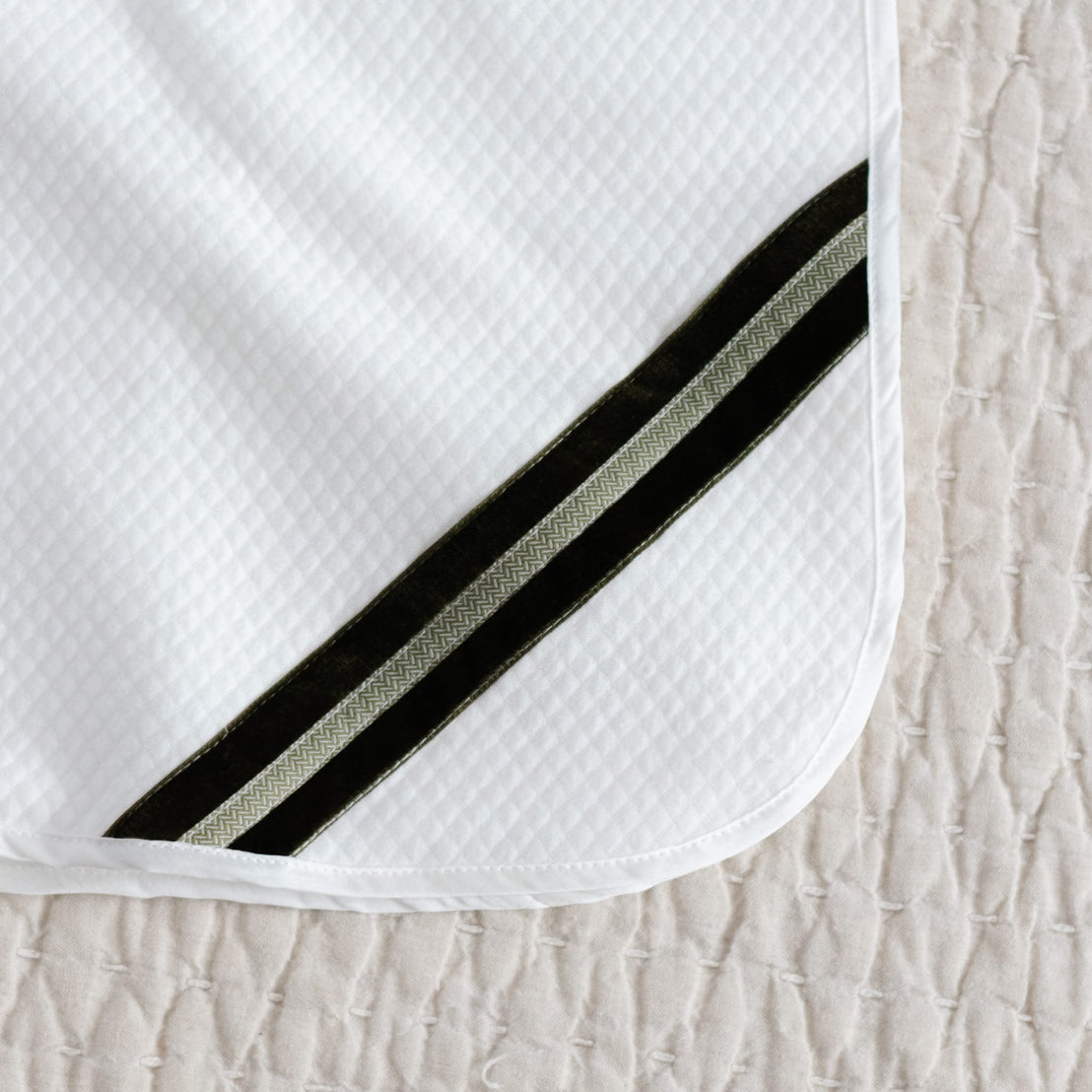 White quilt blanket with green velvet and pattern ribbon detail with silk trim