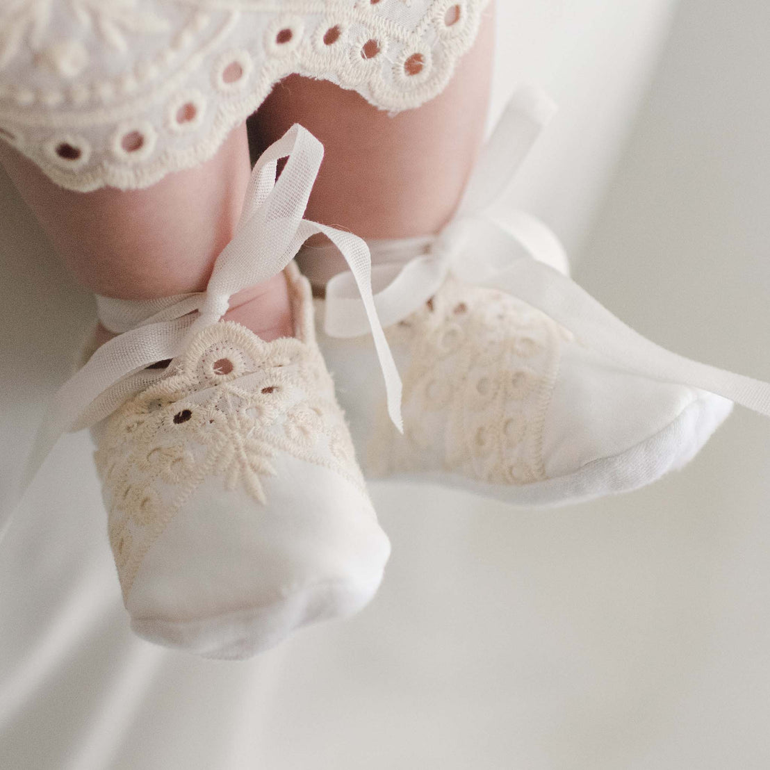 Ingrid Booties made from soft quilted textured cotton and ribbon ties worn by a baby