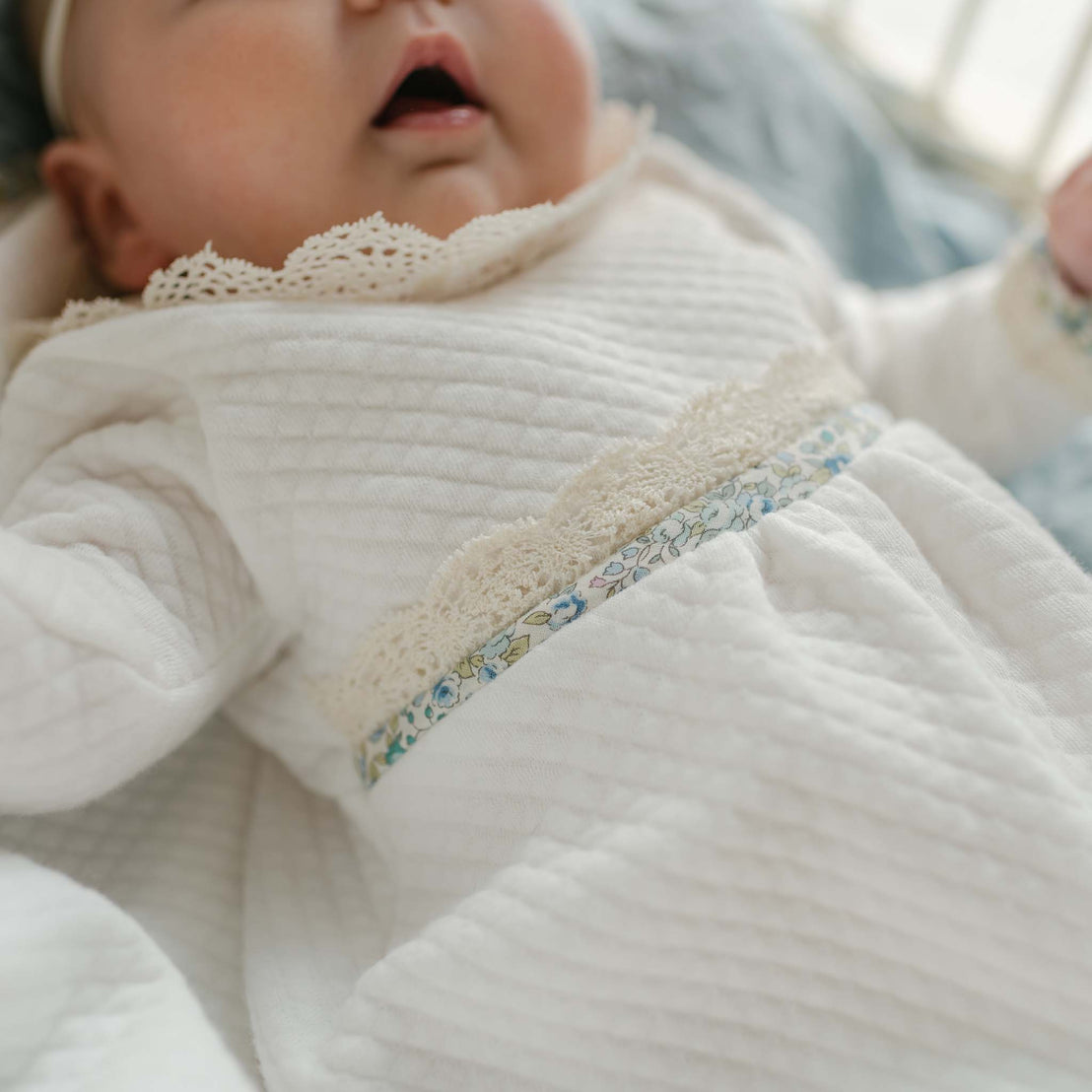 Close-up of the Petite Fleur Blue Romper showing the lace collar and blue floral waistband trim.