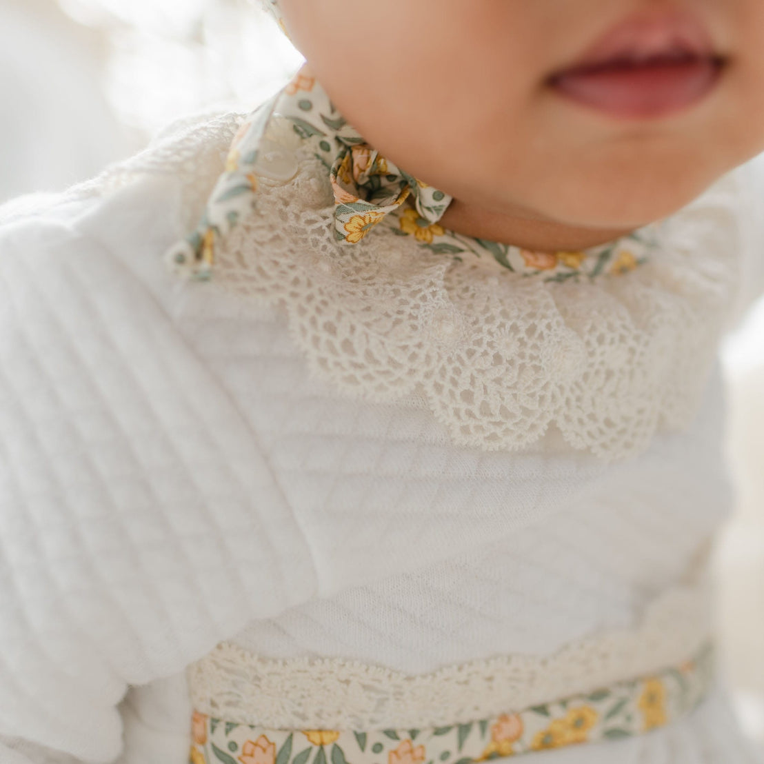 Close-up of the Petite Fleur Yellow Romper collar with lace detail and floral bow at the neckline.