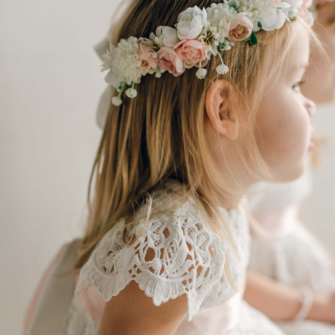 Close-up of a floral crown with white and blush flowers worn with the Lola Girls Lace Dress.
