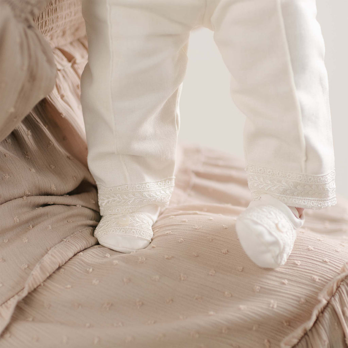 A detail shot of the lace-trimmed pant leg and matching booties from the Oliver Sweater Pants Suit.