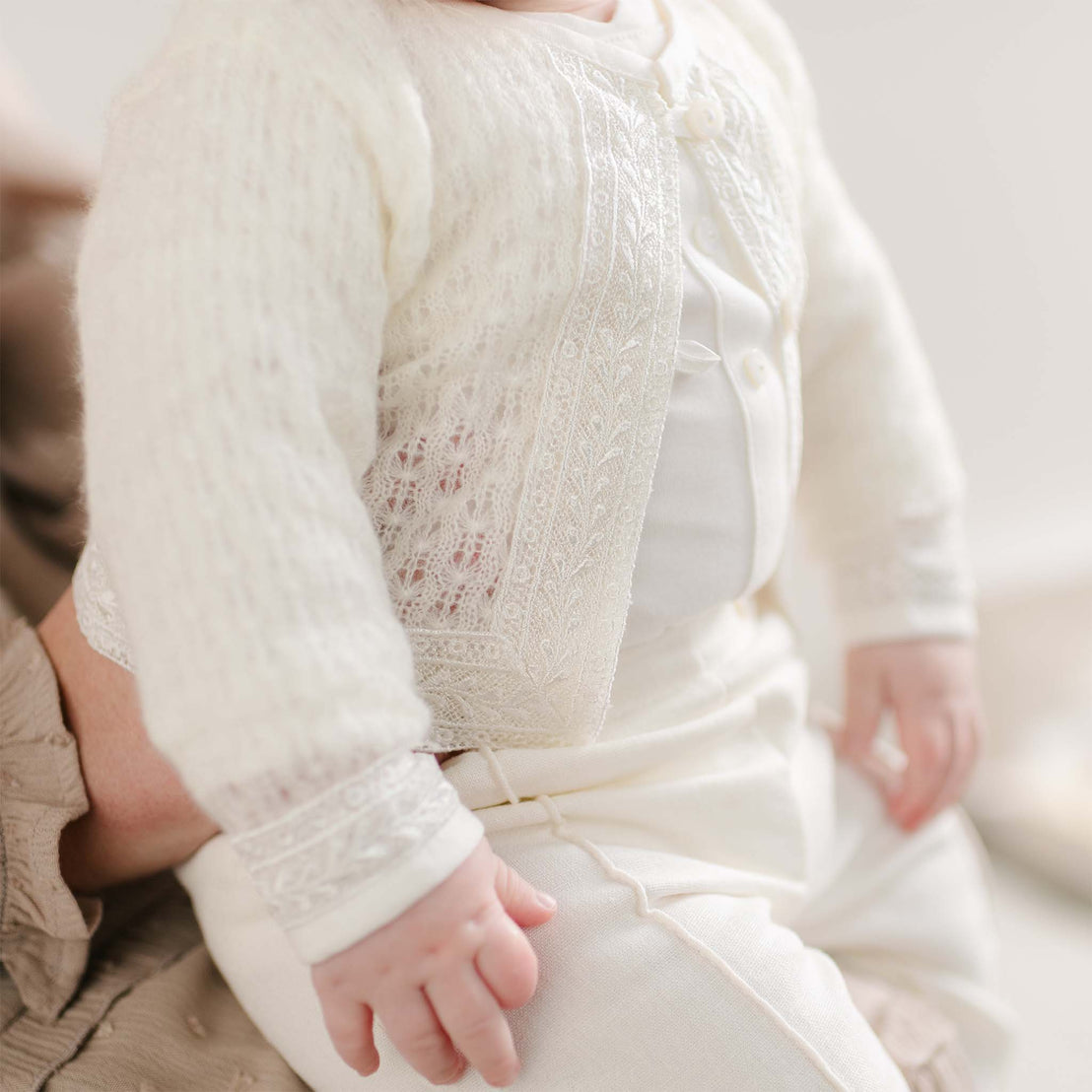 A close-up of the Oliver Sweater Pants Suit, showing the knit sweater’s lace-trimmed front panel and pearlized buttons.
