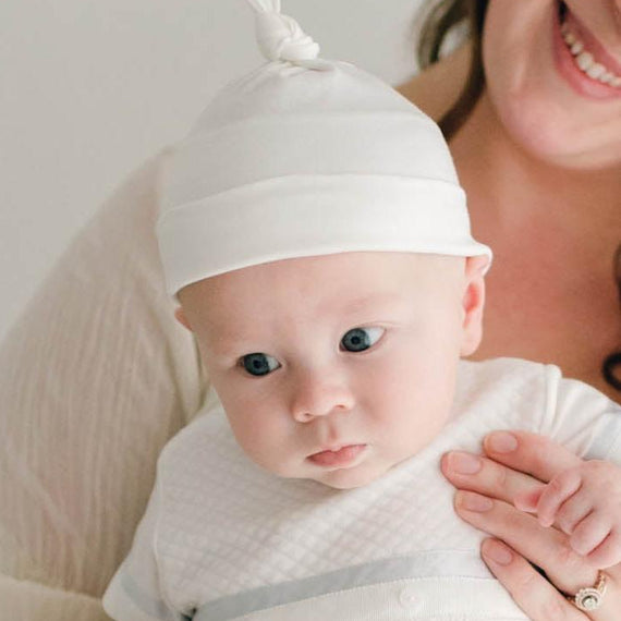 Baby boy being held by his mother. He is wearing the Owen Layette and Knot Cap