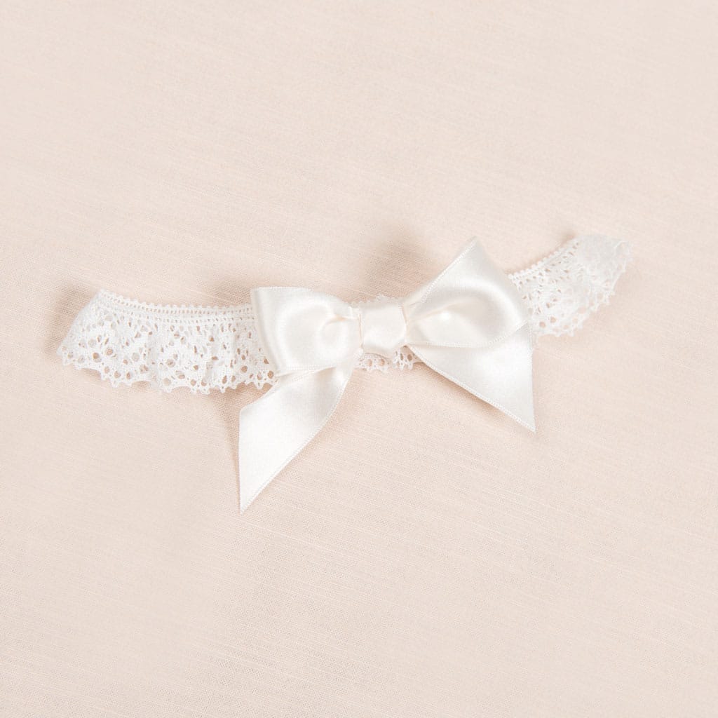 Flat lay photo of a lace headband with bow, part of a christening collection.
