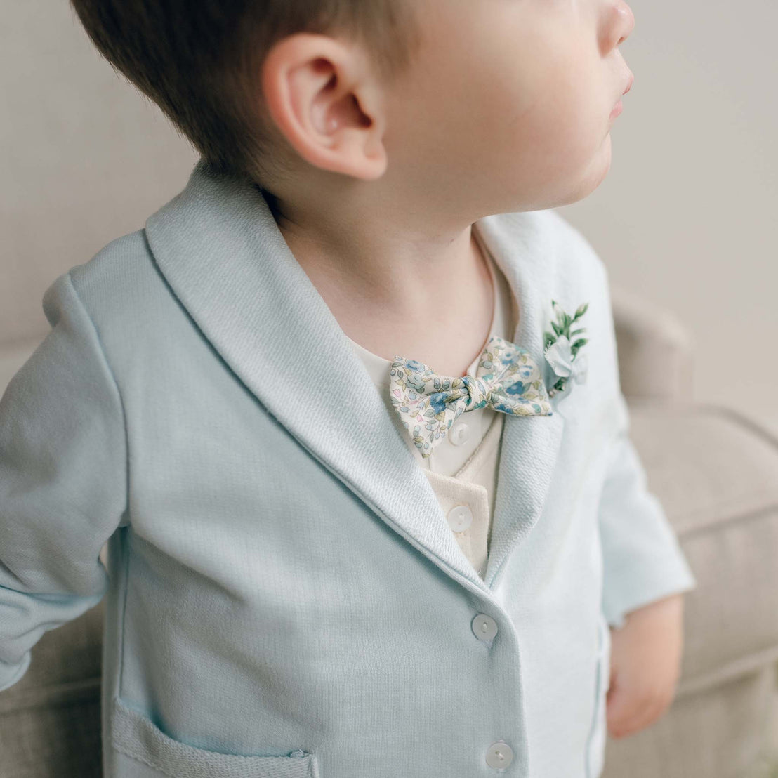 Toddler wearing the Petite Fleur Blue Bow Tie and boutonniere with a light blue jacket.
