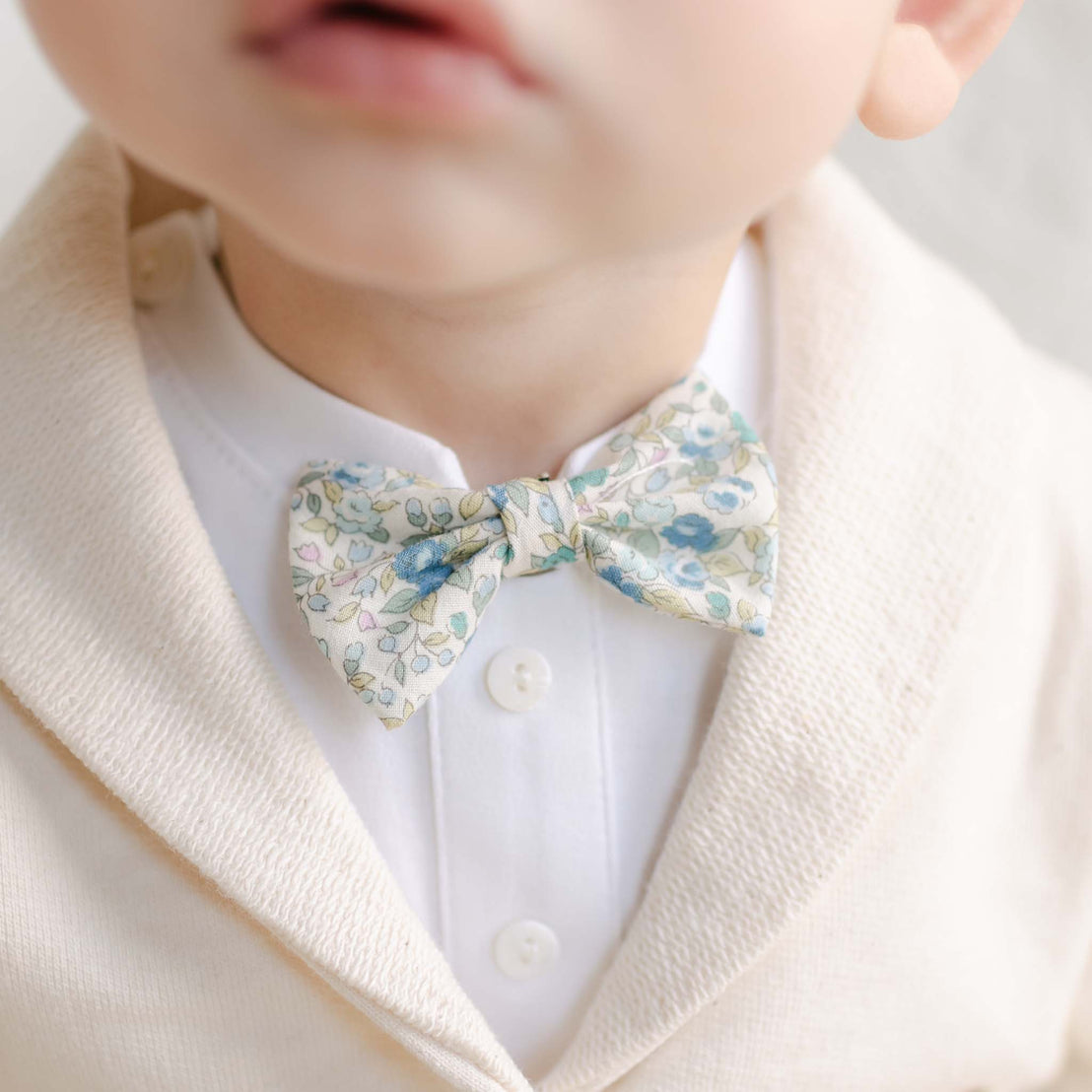 Close-up of the Petite Fleur Blue Bow Tie on a collared white shirt and ivory jacket.