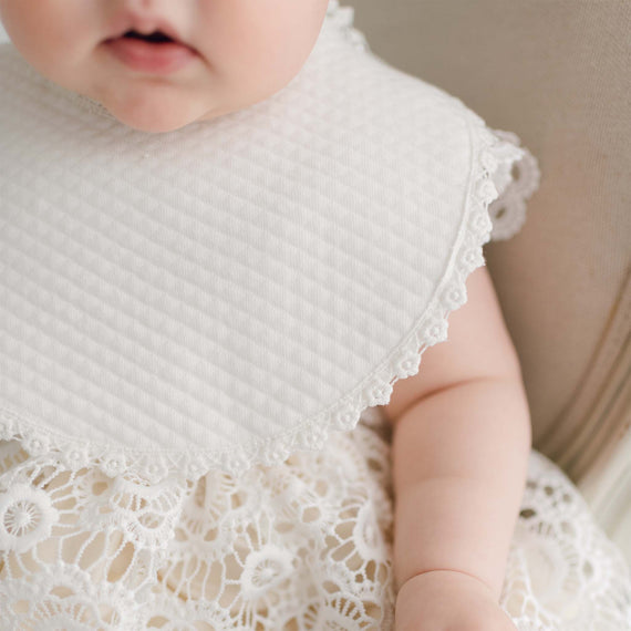 Close-up of a baby wearing the Poppy Bib, showcasing the delicate lace trim.