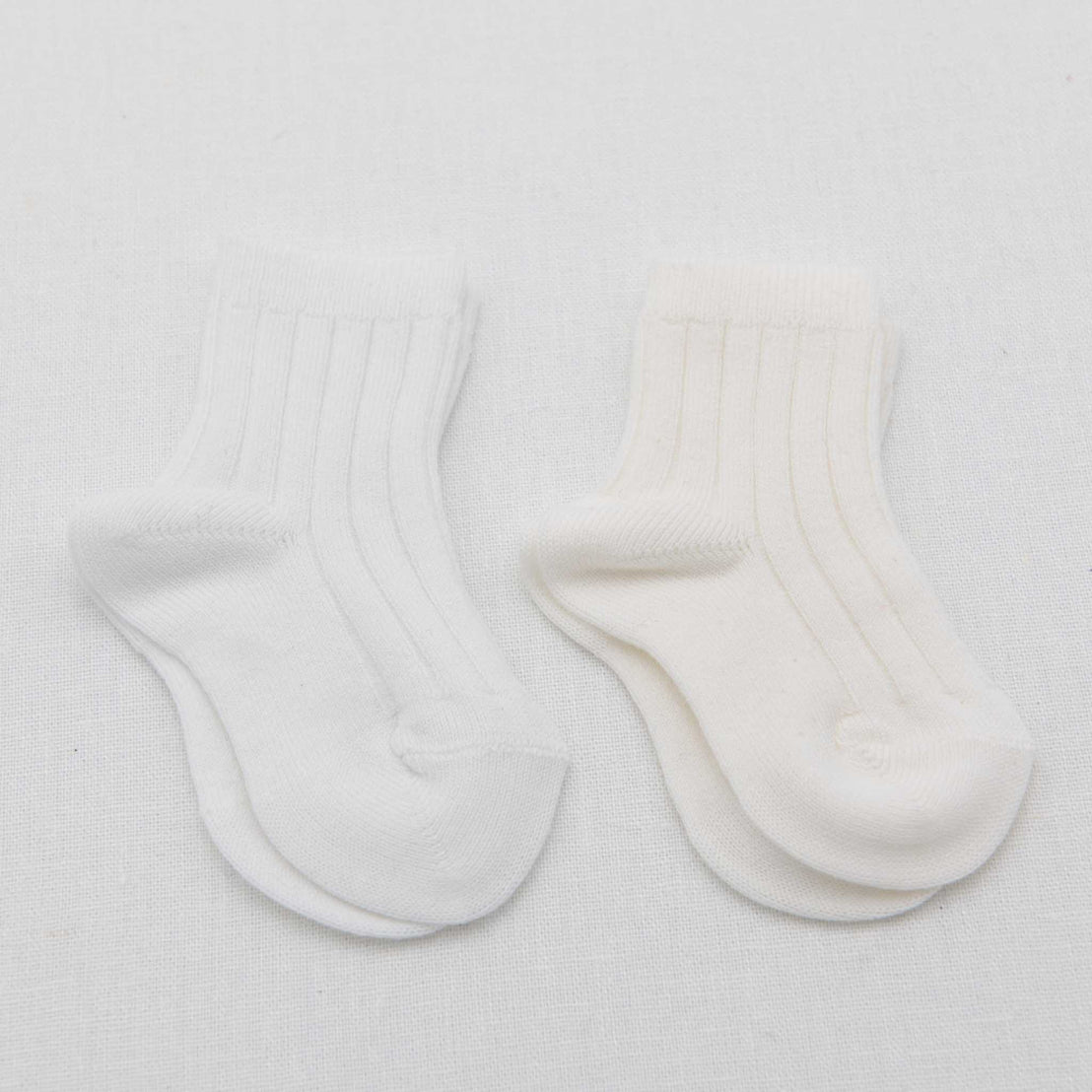 A pair of white vintage Ribbed Socks with ribbed cuffs laid flat on a white textured background.