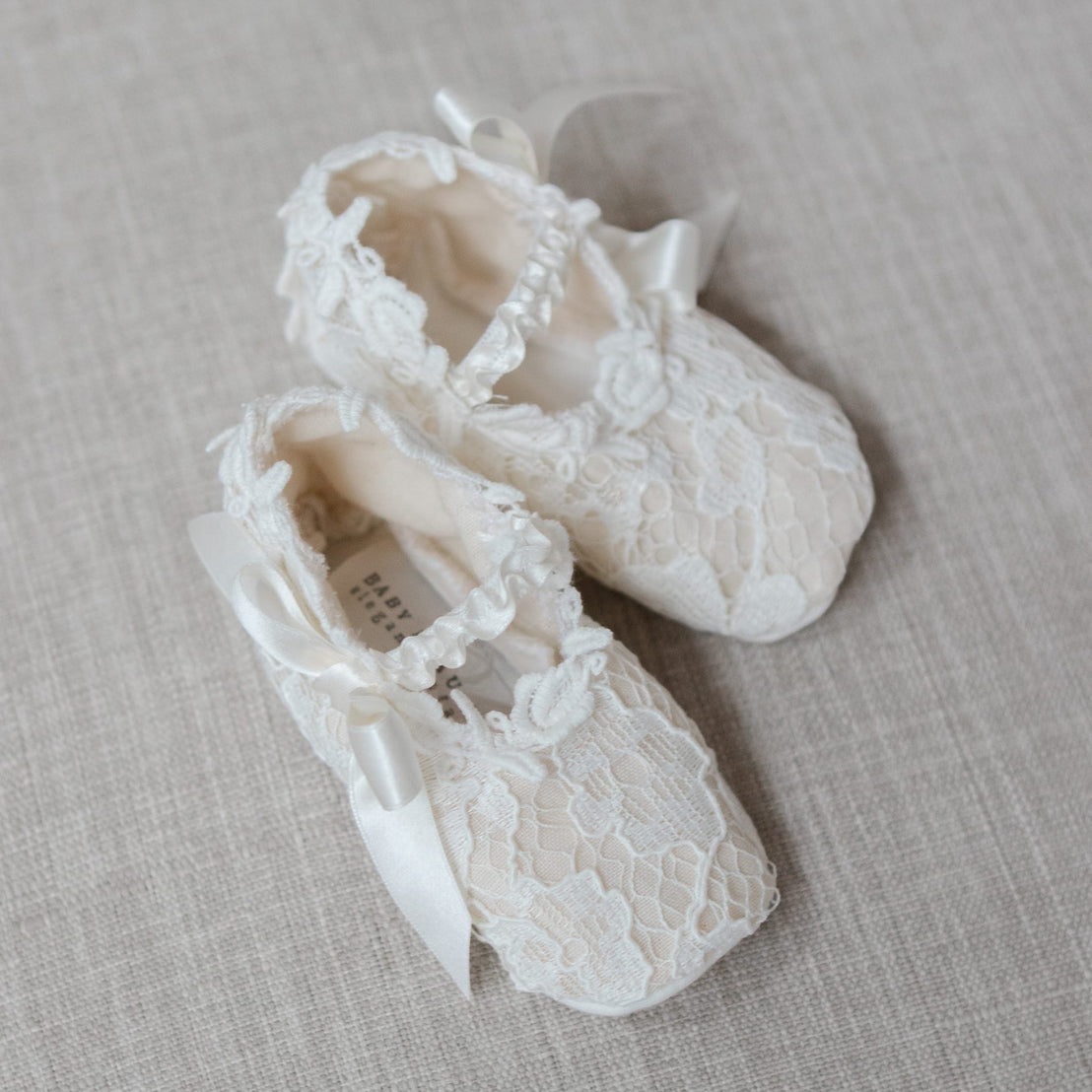 Pair of lace baby shoes on a textured surface