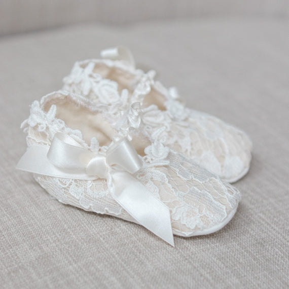 Lace baby shoes with a bow on a light gray background