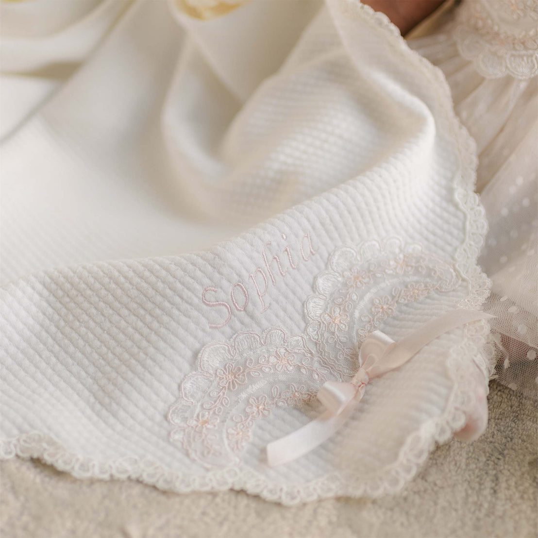 Sophia Blanket with embroidered lace detailing, satin bow, and personalized name in pink thread.