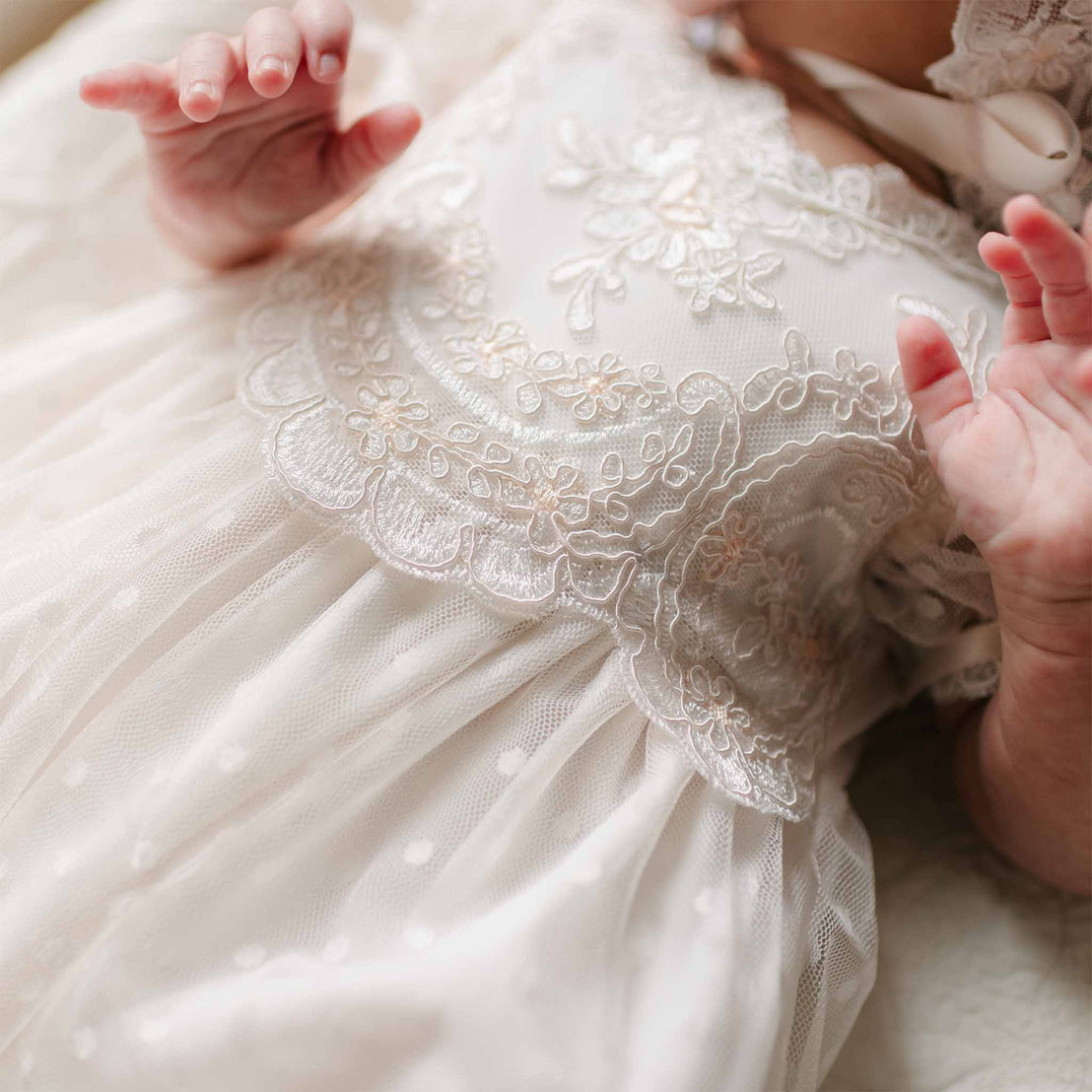 A detailed view of the Sophia Layette’s bodice, showing the intricate floral embroidery and scalloped lace trim.
