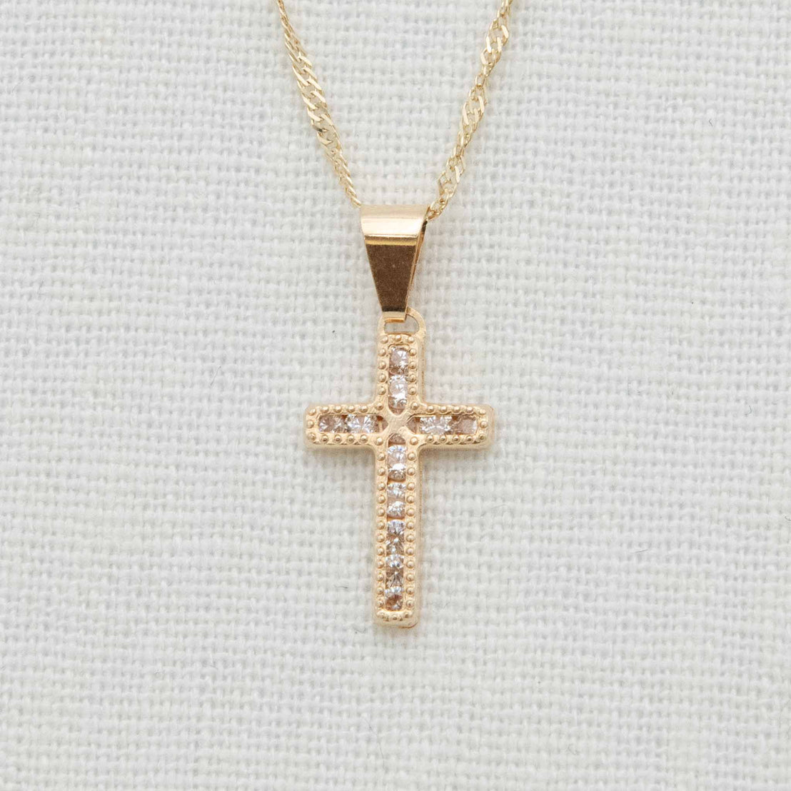 Gold and cubic zirconia cross necklace detail