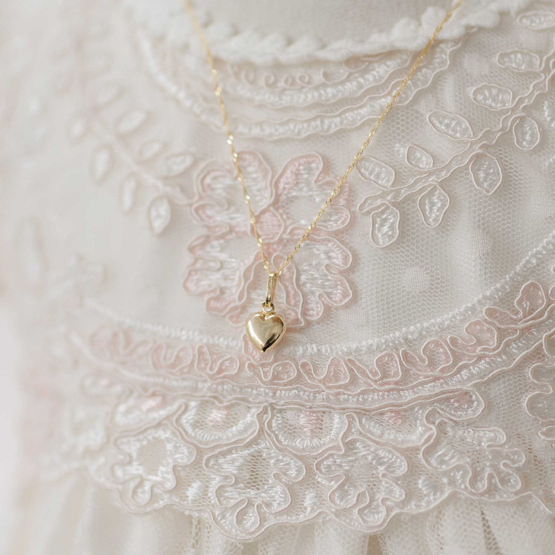 Gold heart-shaped pendant necklace on a lace fabric background