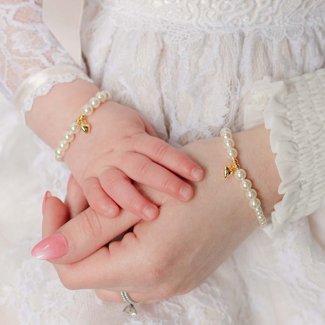 Close-up of mother and baby wearing pearl bracelets with a soft focus background