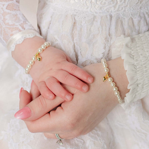 Close-up of mother and baby wearing pearl bracelets with a soft focus background