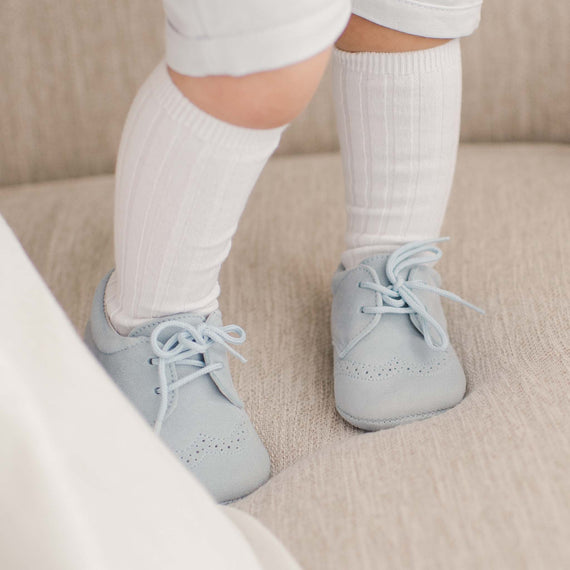 Baby boy wearing the Harrison Suede Shoes that are made with a super soft, light blue suede with detailed edging